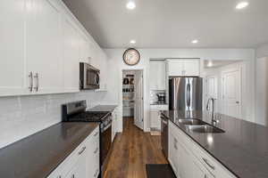 Kitchen with appliances with stainless steel finishes, white cabinetry, tasteful backsplash, recessed lighting, and dark wood finished floors