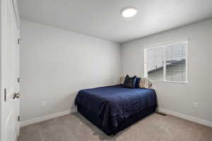 Bedroom featuring light colored carpet and a textured ceiling