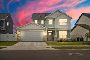 Craftsman inspired home with stone siding, board and batten siding, a gate, concrete driveway, and a garage