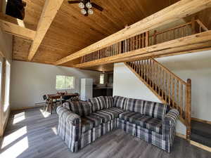 Living area featuring stairs, a wood ceiling with exposed beams, ceiling fan, and wood finished floors