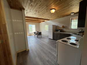 Kitchen with wood ceiling, white appliances, wood finished floors, and a baseboard heating unit