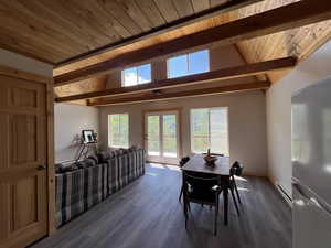 Dining space featuring a wooden ceiling with exposed beams, a baseboard radiator, wood finished floors, and high vaulted ceiling
