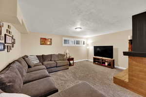 Carpeted living room featuring baseboards and a textured ceiling