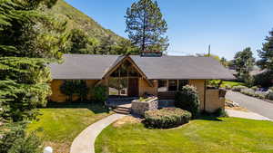 View of front of house featuring a shingled roof, a front lawn, a porch, and brick siding