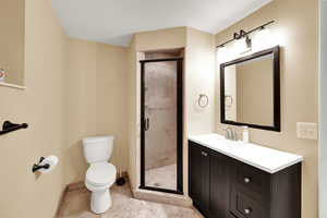 Bathroom featuring vanity, a shower stall, a textured ceiling, and tile patterned floors