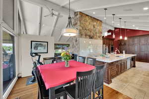 Dining space featuring beam ceiling, a ceiling fan, high vaulted ceiling, and light wood finished floors