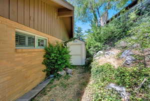View of side of property with a storage shed and brick siding