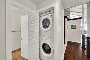 Laundry area featuring stacked washer and clothes dryer and wood finished floors