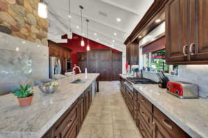 Kitchen featuring light stone countertops, hanging light fixtures, appliances with stainless steel finishes, tasteful backsplash, and recessed lighting
