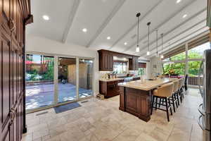 Kitchen with freestanding refrigerator, a kitchen island with sink, a kitchen breakfast bar, hanging light fixtures, and recessed lighting
