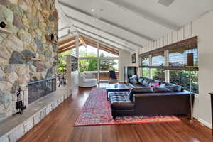 Living area with beamed ceiling, wood finished floors, a fireplace, and high vaulted ceiling