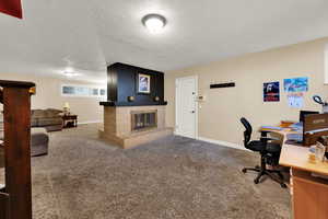 Home office with carpet, a textured ceiling, and a brick fireplace