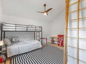 Bedroom 3 with vaulted ceilings, fan, and loft stairs