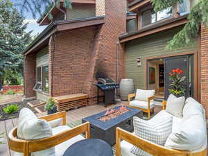 Wooden terrace featuring a grill and an outdoor living space with a fire pit