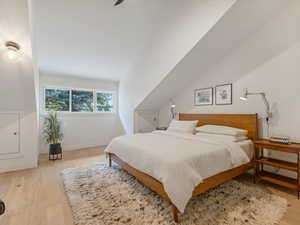 Primary bedroom with vaulted ceilings, swing arm wall sconces, and ceiling fan