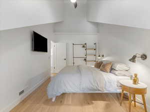 Bedroom 2 featuring vaulted ceilings, hard wired wall sconces and open shelving