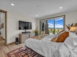 Bedroom featuring access to exterior, light wood-type flooring, and recessed lighting