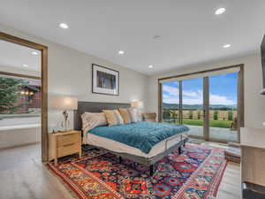 Bedroom with access to outside, light wood-type flooring, a mountain view, recessed lighting, and ensuite bath