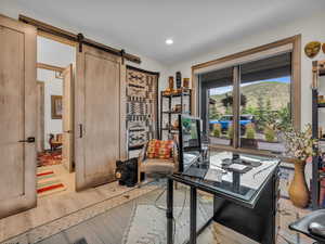 Office area featuring light wood-type flooring, a barn door, and recessed lighting
