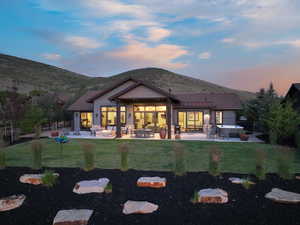 Rear view of property featuring a hot tub, a patio area, a fenced backyard, a standing seam roof, and a mountain view