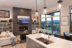 Kitchen with light stone counters, decorative light fixtures, light wood-style flooring, open floor plan, and recessed lighting