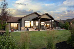 Rear view of property with a patio, an outdoor living space, a yard, and stone siding