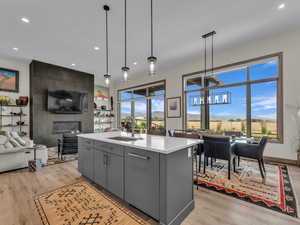 Kitchen with gray cabinetry, light wood-style flooring, light countertops, recessed lighting, and open floor plan