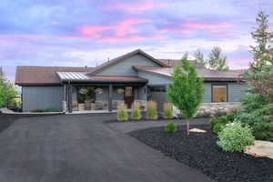 View of front of house featuring stone siding, asphalt driveway, a porch, and an attached garage