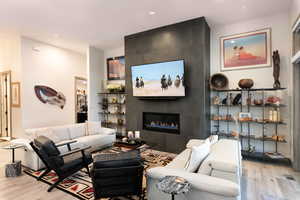 Living room with wood finished floors, a fireplace, and recessed lighting