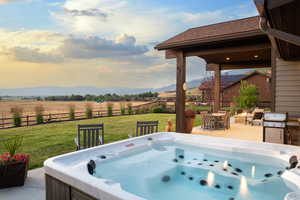 Fenced backyard featuring a hot tub, a mountain view, a view of rural / pastoral area, and outdoor dining area