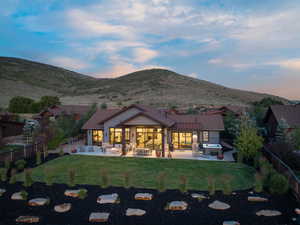 Back of house at dusk featuring a patio area, a fenced backyard, a mountain view, and a jacuzzi