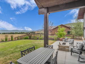 Fenced backyard with an outdoor fire pit, a patio area, a mountain view, and outdoor dining area