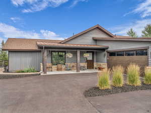 View of front of house featuring a garage, stone siding, and a shingled roof