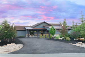 View of front of property featuring asphalt driveway, covered porch, a standing seam roof, a metal roof, and stone siding