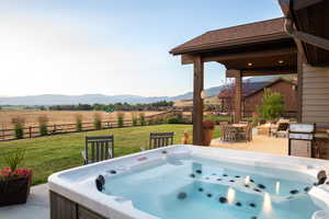 Fenced backyard featuring a hot tub, a mountain view, a rural view, and outdoor dining area