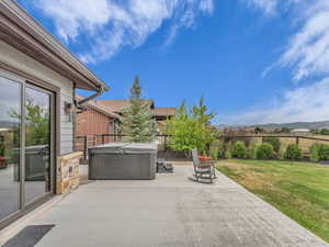 Fenced backyard with a hot tub, a patio, and a mountain view