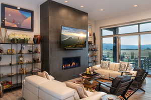 Living room with wood finished floors, recessed lighting, and a tiled fireplace