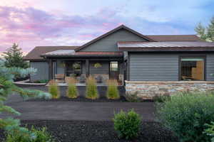 View of front facade featuring stone siding, a standing seam roof, a metal roof, and covered porch