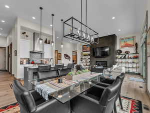 Dining room with light wood finished floors, a large fireplace, and recessed lighting