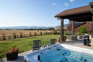 Fenced backyard featuring a mountain view, a view of countryside, a hot tub, a patio area, and outdoor dining area