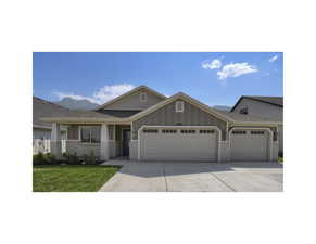 Craftsman-style house with an attached garage, board and batten siding, concrete driveway, and a front yard