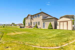 Rear view of house with a shed, a yard, entry steps, a detached carport, and a patio