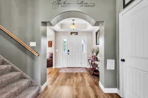 Entrance foyer featuring a tray ceiling, wood finished floors, and stairway
