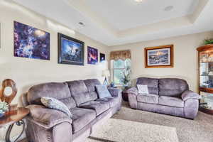 Carpeted living room with a raised ceiling
