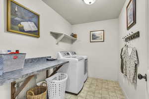 Washroom with washing machine and dryer and light stone finish flooring