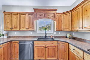 Kitchen with dishwasher, dark countertops, and brown cabinets