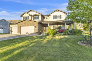 Craftsman house with driveway, stone siding, a front yard, a garage, and board and batten siding