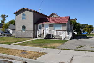 View of front facade with a front yard, brick siding, and a metal roof