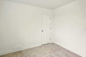 Empty room with light colored carpet and baseboards