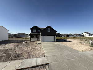 View of front facade featuring concrete driveway, an attached garage, a residential view, and covered porch